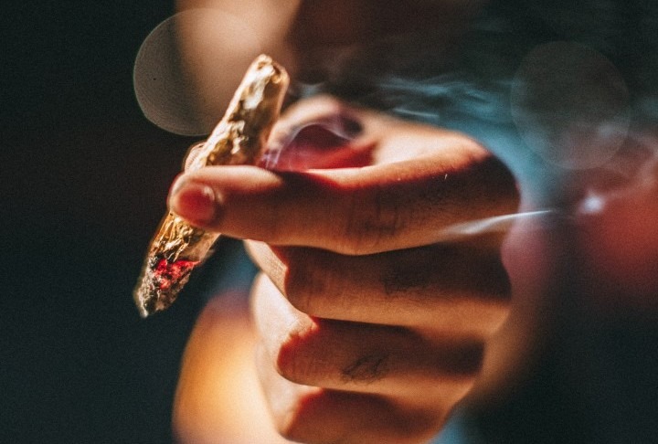 Eine Person hält einen schlecht gebauten Joint in die Kamera